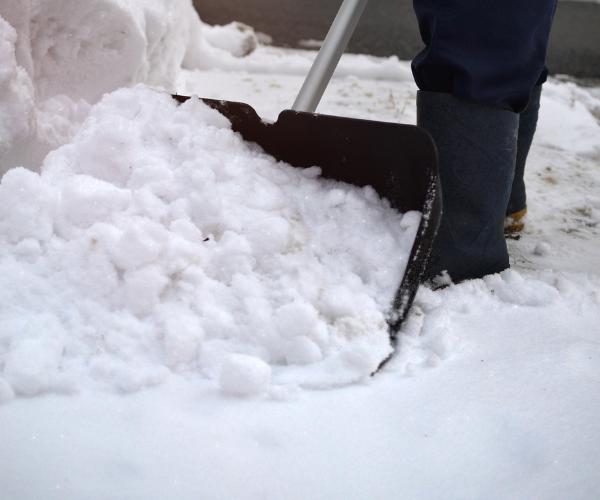 Lucky's Landscaping and Tree Service shoveling snow from a walkway, providing residential snow removal services.