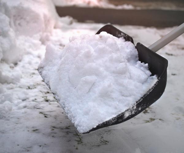 Snow shovel lifting heavy snow from a driveway after a recent winter storm in Northern Virginia.